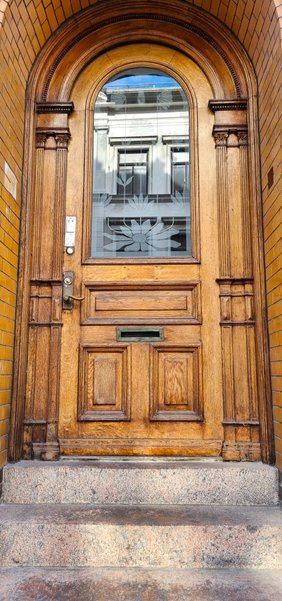 Restaurerad portdörr i trä med välvt överljus